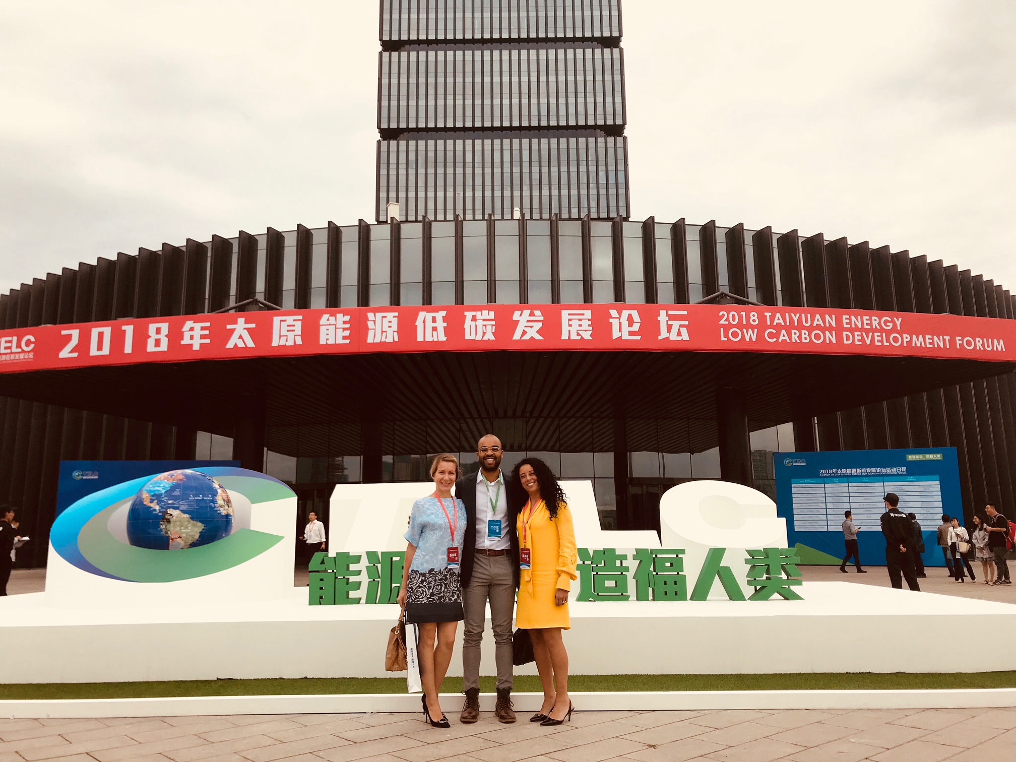 Three people pose in front of Chinese convention center